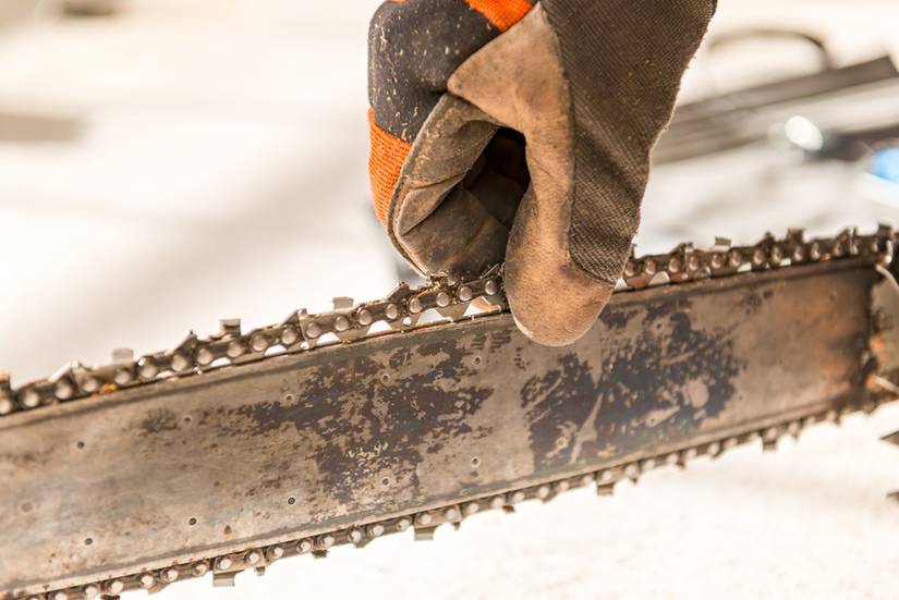 Hands with gloves holding the chainsaw