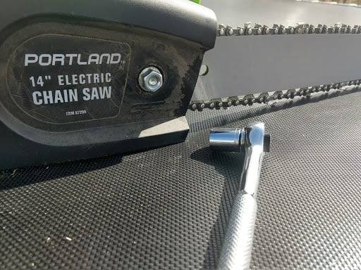 Chainsaw and a socket wrench laid down on a flat surface