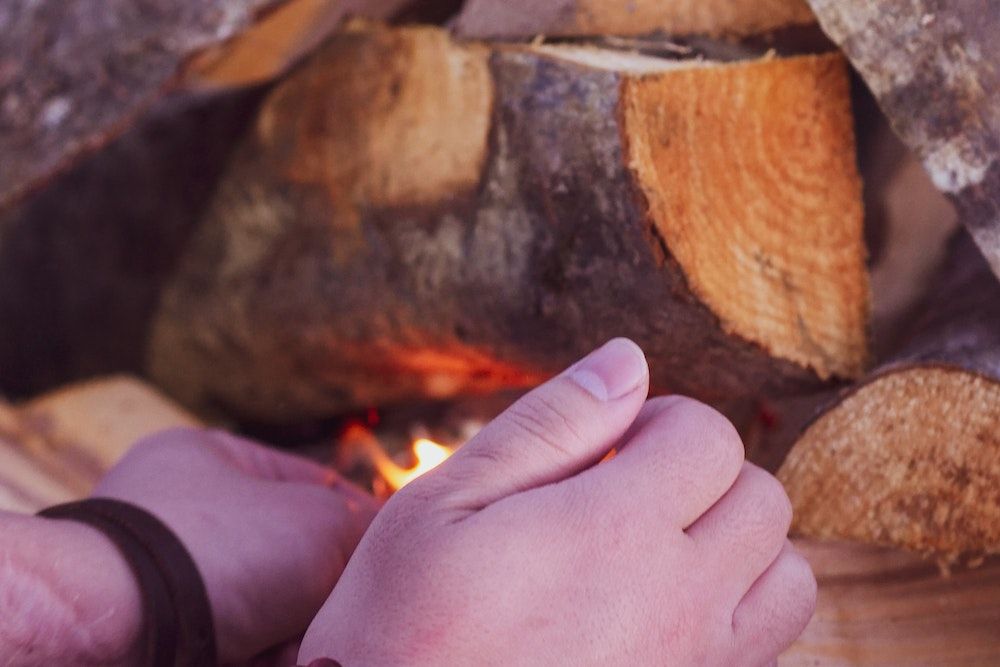 close up of hands lighting a wood fire