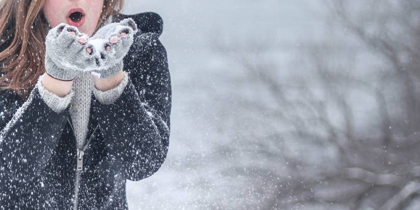 Person blowing snowflakes on a snowy winter day
