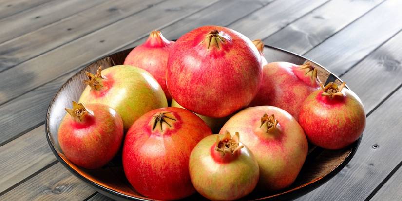 Wooden bowl of pomegranate fruits