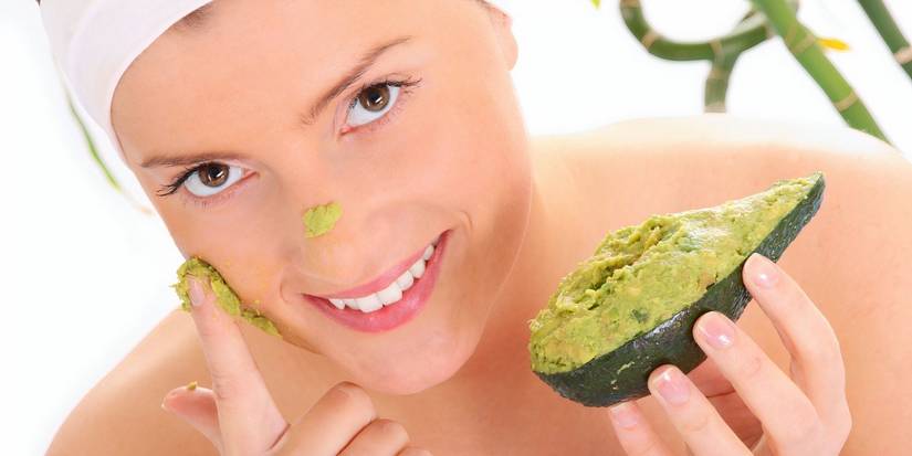 A woman applying an avocado mask on her face