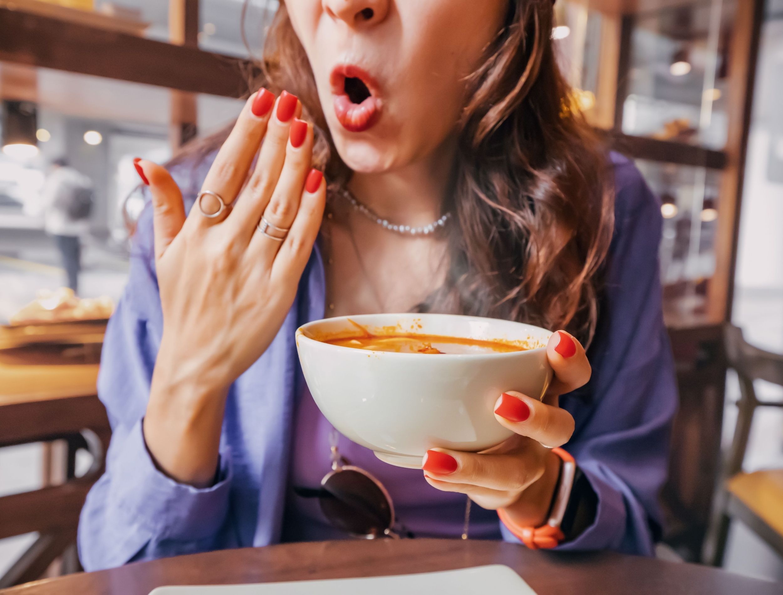 Woman eating a spicy pepper soup 